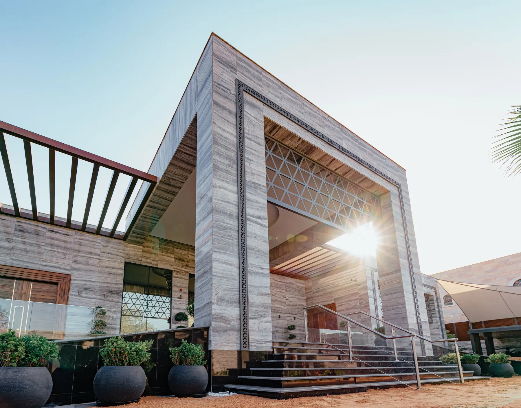 Entrance of a private villa with a glass façade, timber ceiling slats and stone cladding