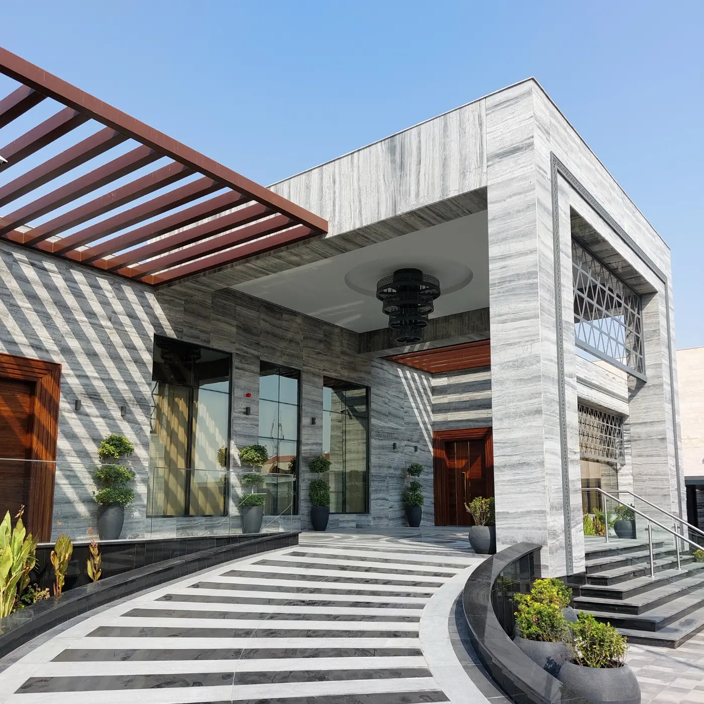 Villa entrance walkway with glass walls and a timber pergola