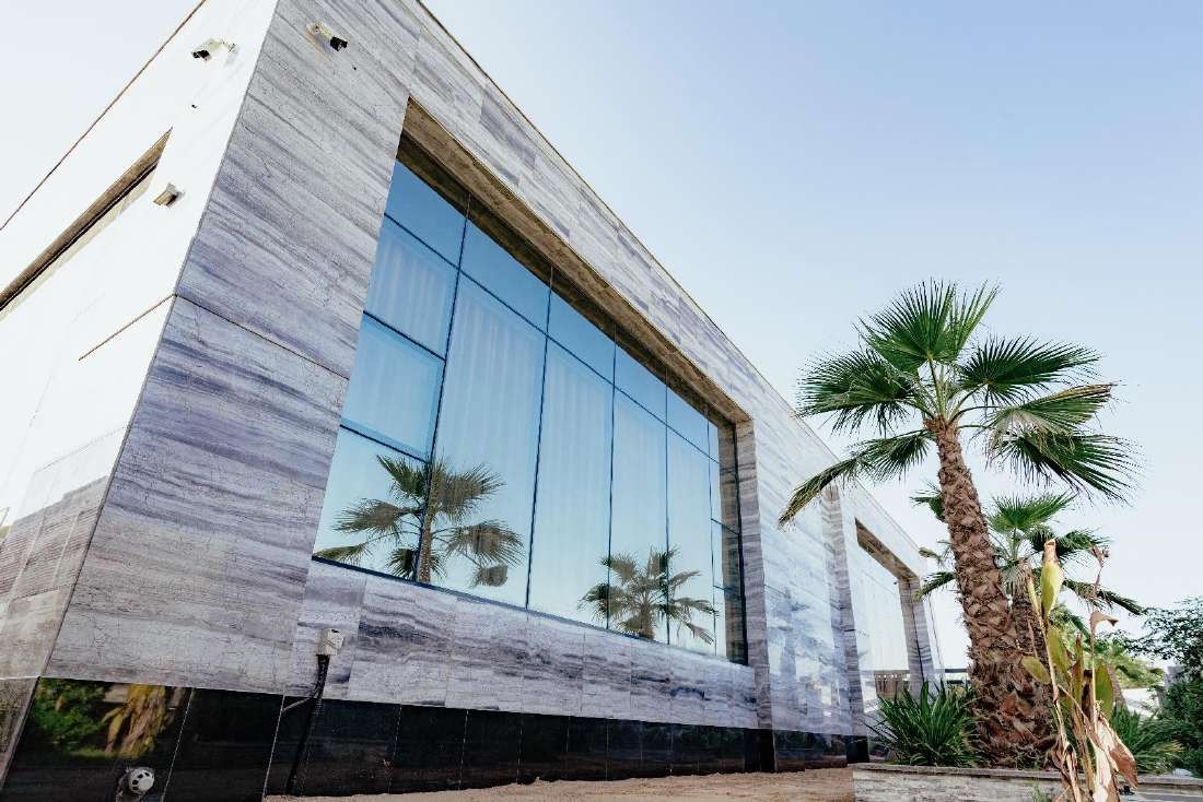 Travertine villa with a large glass box façade and palm trees